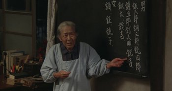 Movie still from “Rhapsody in August” (1991), directed by Akira Kurosawa – An old man standing in front of a blackboard; Medium shot, High angle