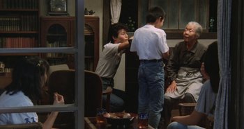 Movie still from “Rhapsody in August” (1991), directed by Akira Kurosawa – A group of people sitting around a table; Wide shot, Over the shoulder angle