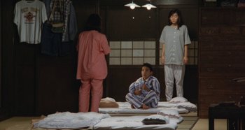 Movie still from “Rhapsody in August” (1991), directed by Akira Kurosawa – A group of people standing around a room; Wide shot, High angle
