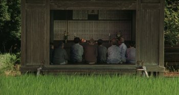 Movie still from “Rhapsody in August” (1991), directed by Akira Kurosawa – A group of people sitting in front of a wall; Extreme Wide shot, High angle
