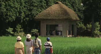 Movie still from “Rhapsody in August” (1991), directed by Akira Kurosawa – A group of people standing in front of a straw hut; Extreme Wide shot, High angle