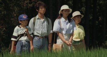 Movie still from “Rhapsody in August” (1991), directed by Akira Kurosawa – A group of people standing next to each other in the grass; Medium shot, Low angle