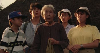 Movie still from “Rhapsody in August” (1991), directed by Akira Kurosawa – An old woman standing in front of a group of young people; Medium shot, High angle