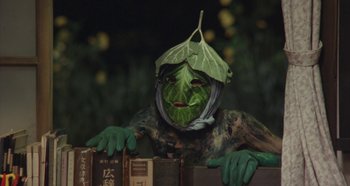 Movie still from “Rhapsody in August” (1991), directed by Akira Kurosawa – A person with a leaf on their head and face; Medium shot, High angle