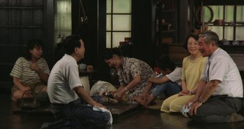 Movie still from “Rhapsody in August” (1991), directed by Akira Kurosawa – A group of people sitting on the floor in a living room; Wide shot, High angle