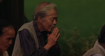 Movie still from “Rhapsody in August” (1991), directed by Akira Kurosawa – An older woman is praying with her hands in front of her face; Close Up shot, High angle