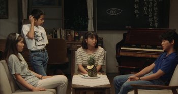 Movie still from “Rhapsody in August” (1991), directed by Akira Kurosawa – A group of people sitting around a table with a pineapple on top of it; Wide shot, High angle