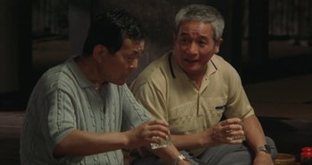 Movie still from “Rhapsody in August” (1991), directed by Akira Kurosawa – Two older asian men sitting next to each other; Medium shot, High angle