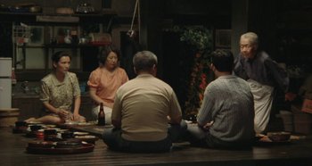 Movie still from “Rhapsody in August” (1991), directed by Akira Kurosawa – A group of people sitting on a wooden floor; Wide shot, High angle