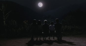 Movie still from “Rhapsody in August” (1991), directed by Akira Kurosawa – A group of people sitting in the dark under a full moon; Wide shot, High angle