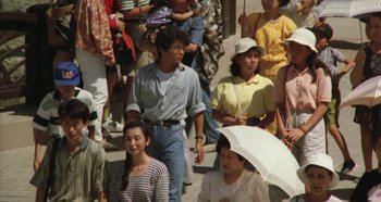 Movie still from “Rhapsody in August” (1991), directed by Akira Kurosawa – A group of people standing on the sidewalk; Medium shot, High angle