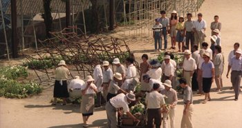Movie still from “Rhapsody in August” (1991), directed by Akira Kurosawa – A group of people standing next to each other on a street; Extreme Wide shot, High angle