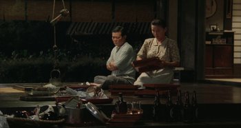Movie still from “Rhapsody in August” (1991), directed by Akira Kurosawa – A man and a woman sitting in front of a table; Wide shot, High angle