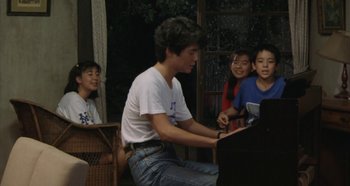 Movie still from “Rhapsody in August” (1991), directed by Akira Kurosawa – A man sitting in front of a grand piano; Medium shot, High angle