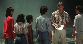 Movie still from “Rhapsody in August” (1991), directed by Akira Kurosawa – A group of people standing next to each other near a body of water; Medium shot, Over the shoulder angle