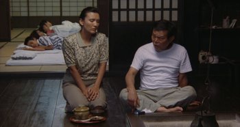 Movie still from “Rhapsody in August” (1991), directed by Akira Kurosawa – A man and a woman sitting on the floor; Medium shot, High angle