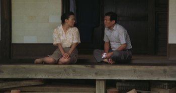 Movie still from “Rhapsody in August” (1991), directed by Akira Kurosawa – A man and a woman sitting on top of a wooden bench; Medium shot, High angle