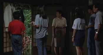 Movie still from “Rhapsody in August” (1991), directed by Akira Kurosawa – A group of people standing in front of a door; Wide shot, High angle