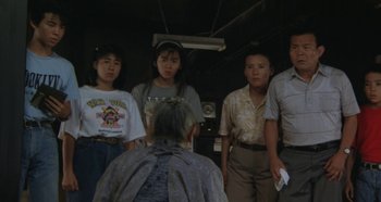 Movie still from “Rhapsody in August” (1991), directed by Akira Kurosawa – A group of people standing in front of a person; Medium shot, High angle