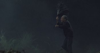 Movie still from “Rhapsody in August” (1991), directed by Akira Kurosawa – An older man holding a black umbrella in the dark; Wide shot, Low angle