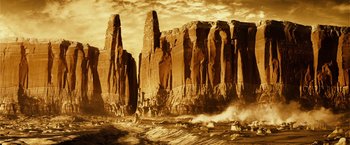 Movie still from “Riddick” (2013), directed by David Twohy – A very tall rock formation in the middle of the desert; Extreme Wide shot, Low angle