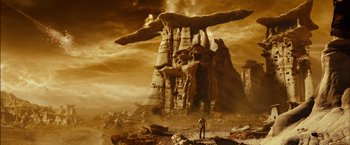 Movie still from “Riddick” (2013), directed by David Twohy – A man standing in front of an enormous rock structure; Extreme Wide shot, Low angle