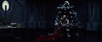 Movie still from “Riddick” (2013), directed by David Twohy – A man and a woman sitting on a chair; Wide shot, High angle