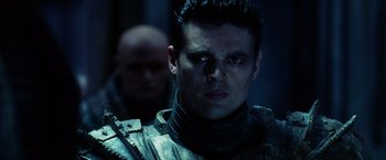 Movie still from “Riddick” (2013), directed by David Twohy – A person wearing a suit; Close Up shot, Over the shoulder angle