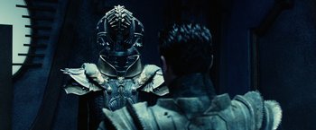 Movie still from “Riddick” (2013), directed by David Twohy – A man is looking into a mirror while another man looks at him; Medium shot, Over the shoulder angle