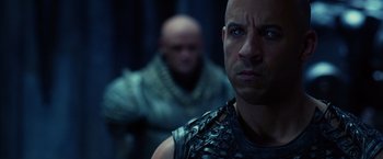 Movie still from “Riddick” (2013), directed by David Twohy – A man in chains is looking at the camera; Close Up shot, Over the shoulder angle