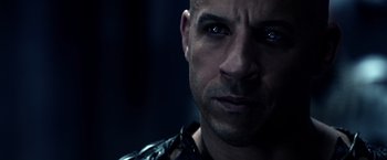 Movie still from “Riddick” (2013), directed by David Twohy – A person with a chain around his neck; Close Up shot, Over the shoulder angle