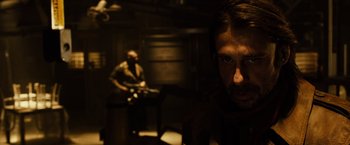 Movie still from “Riddick” (2013), directed by David Twohy – A man with a beard is looking at the camera; Close Up shot, Over the shoulder angle