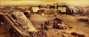 Movie still from “Riddick” (2013), directed by David Twohy – A group of people standing on top of a dirt field; Extreme Wide shot, High angle