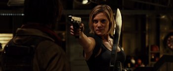 Movie still from “Riddick” (2013), directed by David Twohy – A woman holding a gun in front of a mirror; Medium shot, Over the shoulder angle