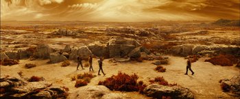 Movie still from “Riddick” (2013), directed by David Twohy – Three people walking across a barren desert landscape; Extreme Wide shot, High angle