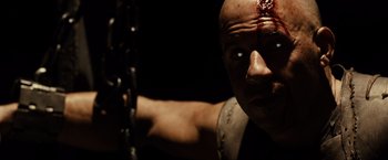 Movie still from “Riddick” (2013), directed by David Twohy – A man with a bandage on his head and neck; Close Up shot, High angle