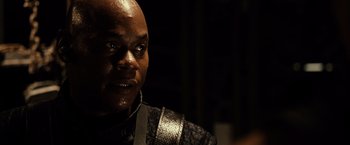 Movie still from “Riddick” (2013), directed by David Twohy – A person wearing a black and silver jacket; Close Up shot, Over the shoulder angle