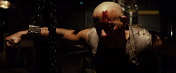 Movie still from “Riddick” (2013), directed by David Twohy – A man with a knife in his hand and blood on his face; Close Up shot, High angle