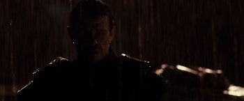 Movie still from “Riddick” (2013), directed by David Twohy – A man standing in the rain with a knife in his hand; Close Up shot, Low angle