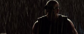 Movie still from “Riddick” (2013), directed by David Twohy – A man in a black shirt is standing in the rain; Close Up shot, Low angle