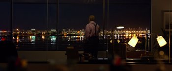 Movie still from “Ride Along 2” (2016), directed by Tim Story – A man standing in front of a window looking out at a city; Wide shot, Over the shoulder angle