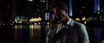 Movie still from “Ride Along 2” (2016), directed by Tim Story – A man talking on a cell phone while standing in front of a body of water at night; Close Up shot, Over the shoulder angle