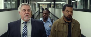 Movie still from “Ride Along 2” (2016), directed by Tim Story – A group of men walking down a hall way; Medium shot, Over the shoulder angle
