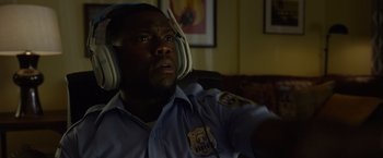 Movie still from “Ride Along 2” (2016), directed by Tim Story – A police officer wearing headphones and looking into the distance; Close Up shot, Over the shoulder angle