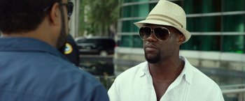 Movie still from “Ride Along 2” (2016), directed by Tim Story – A man wearing a hat and sunglasses talking to another man; Close Up shot, Over the shoulder angle