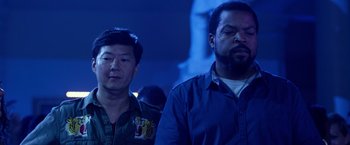 Movie still from “Ride Along 2” (2016), directed by Tim Story – Two men standing next to each other in front of a statue; Medium shot, Low angle