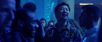 Movie still from “Ride Along 2” (2016), directed by Tim Story – A group of people in a room with a blue light; Medium shot, Over the shoulder angle