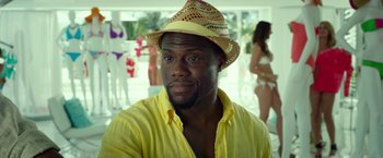 Movie still from “Ride Along 2” (2016), directed by Tim Story – A person wearing a hat and a yellow shirt; Close Up shot, Over the shoulder angle