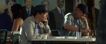 Movie still from “Ride Along 2” (2016), directed by Tim Story – A man sitting at a table in front of a computer; Medium shot, Over the shoulder angle
