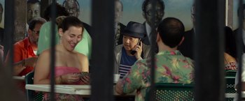 Movie still from “Ride Along 2” (2016), directed by Tim Story – A group of people sitting at a table talking on cell phones; Medium shot, Over the shoulder angle
